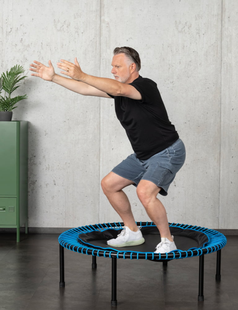 Mann in kurzer Hose macht Übungen auf einem blauen bellicon-Trampolin